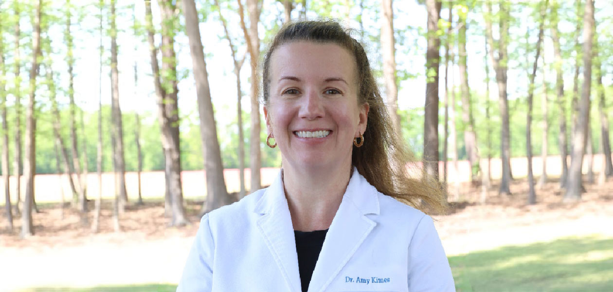 Dr. Amy Kinces, a friendly dentist at Mount Olive Family Dentistry, smiling outdoors in a natural se.